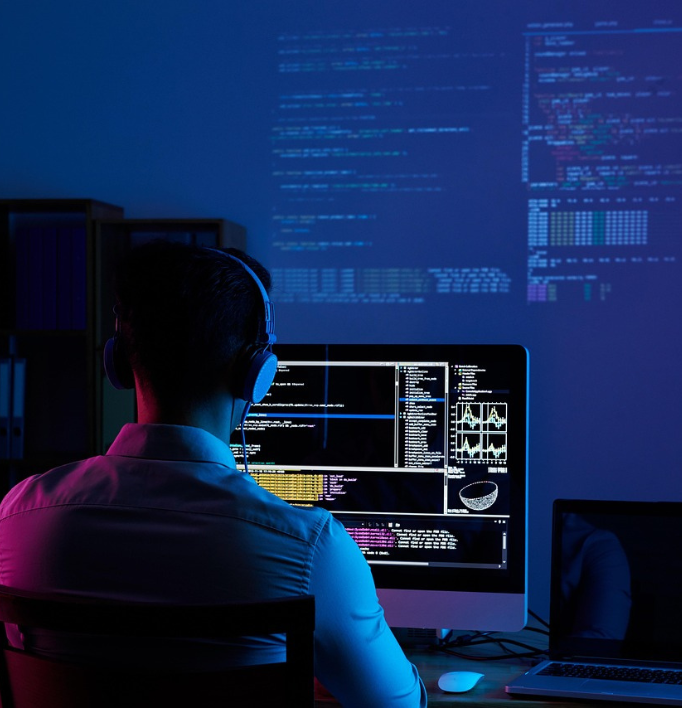 a man in white shirt working on the computer researching with headphones on
